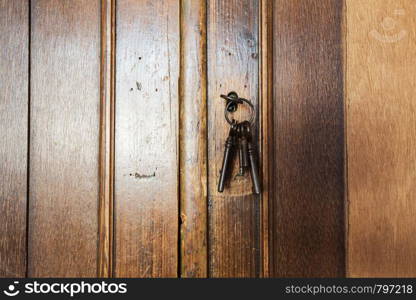 Old rusty keys inside a keyhole of an old antique closet. vintage design close-up. Old rusty keys inside a keyhole of an old antique closet. vintage design