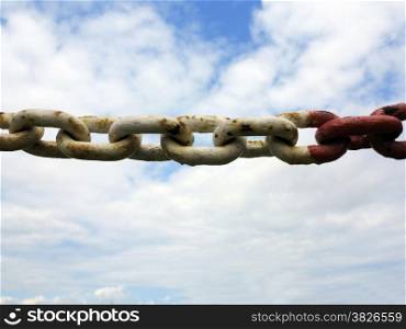 Old rusty metal steel red white chain links segment. Sky cloudy background.