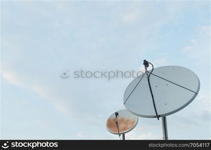 Old rusty old white satellite dishes through use on sky background