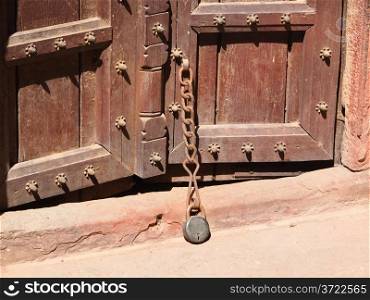 Old rusty padlock and chain on the rural wooden gate