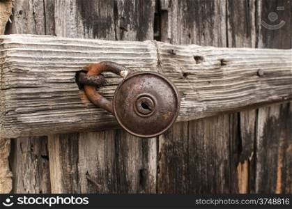 Old rusty padlock on weathered wooden door closeup