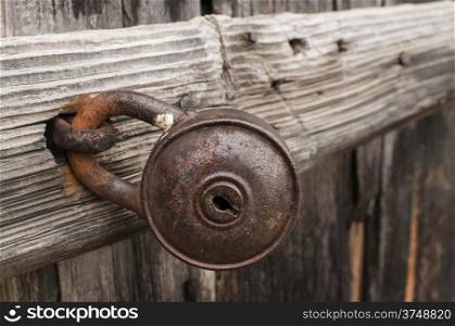 Old rusty padlock on weathered wooden door closeup