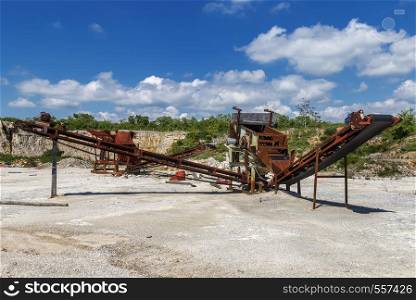 Old rusty stone crushing machines in abandoned quarry
