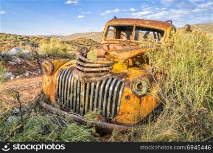 old rusty towing truck at Colorado foothills overgrown by bushes