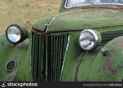 Old rusty vintage car in a field.