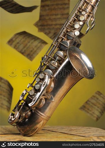 Old saxophone and flying musical notes on a background. The Musical instrument standing on notes with classical music of the beginning of 17 centuries