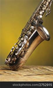 Old saxophone and notes. The Musical instrument standing on notes with classical music of the beginning of 17 centuries