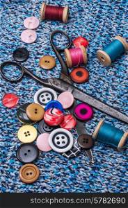 old scissors and thread and buttons on textured background fabric. working dressmaker accessories