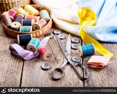 Old scissors, buttons, threads on a wooden table