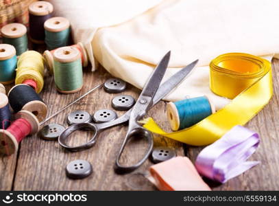 Old scissors, buttons, threads on a wooden table