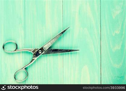Old scissors on a wooden work table. Image toned with retro vintage filter