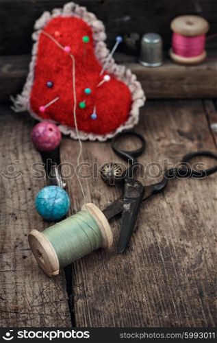 Old scissors,spools of thread,buttons and beads on wooden table