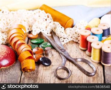 old scissors, various threads and sewing tools on wooden background