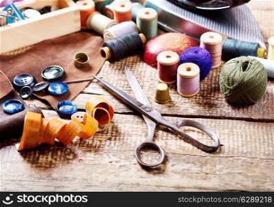 old scissors, various threads and sewing tools on wooden table