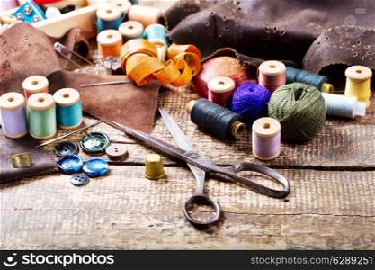 old scissors, various threads and sewing tools on wooden table