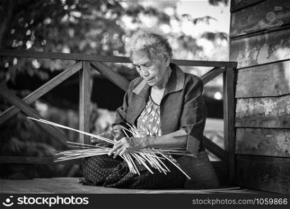 Old senior woman hand working crafts weaving bamboo making basket for nature product in Thailand Asia