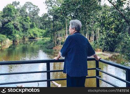 old senior woman looking at river lake pond view