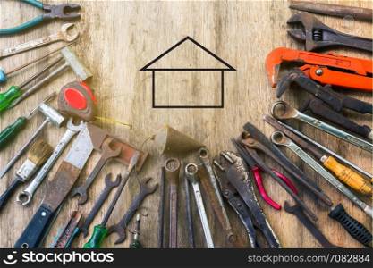 Old set of work tool on wooden background with icon of house in space,industry and engineer tool concept