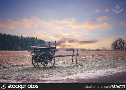 Old settlers wagon standing in the frost on a praerie in the sunset