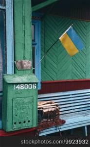 Old shabby mailbox on wooden wall of rural house and national flag of Ukraine
