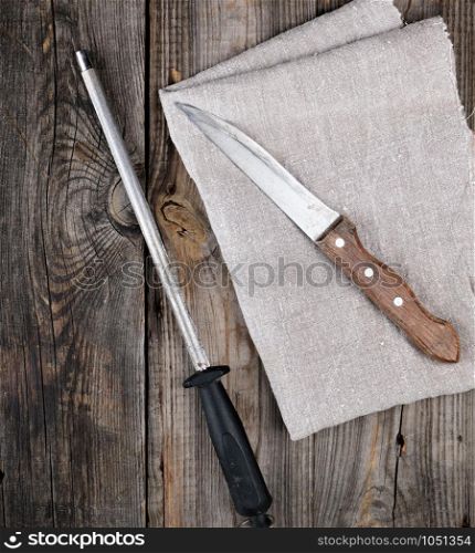 old sharp knife and sharpener with a handle on a gray wooden background, top view