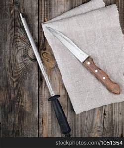 old sharp knife and sharpener with a handle on a gray wooden background, top view