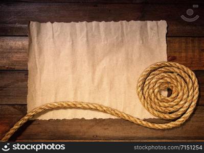 old sheet of parchment or paper lying on wooden boards and a coarse rope pulled into a nautical knot forming a frame. nautical knot paper