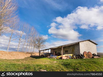 old shelter for agricultural tools, with trees in the background