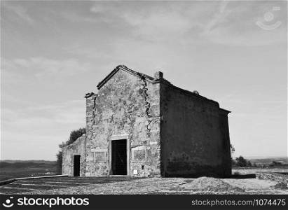 Old small building in black and white, with large cracks that mark the passage of time and its deterioration