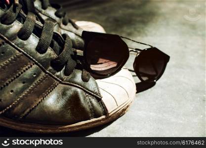 Old sneakers and sunglasses closeup