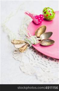 Old spoon with a ribbon on a pink plate with Easter egg