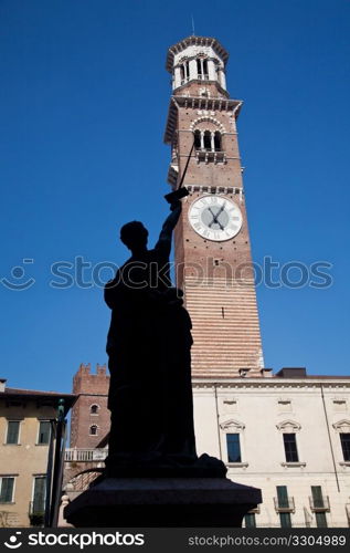 Old statue points at Lamberti Tower in Erbe square in Verona