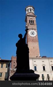 Old statue points at Lamberti Tower in Erbe square in Verona