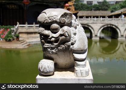 Old stone lion near lake in buddhist temple, China
