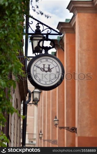 old street clock on the background of a narrow street in Stockholm, Sweden