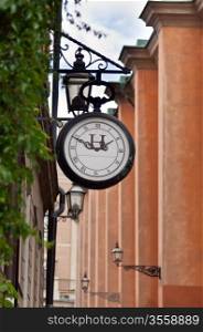 old street clock on the background of a narrow street in Stockholm, Sweden