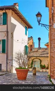 Old street with big flowerpot in Santarcangelo di Romagna town, Rinini Province, Italy. Italian cityscape