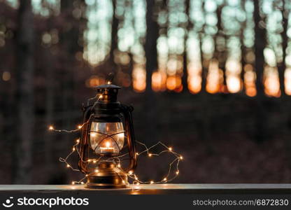 Old style lantern with lights over woodland background