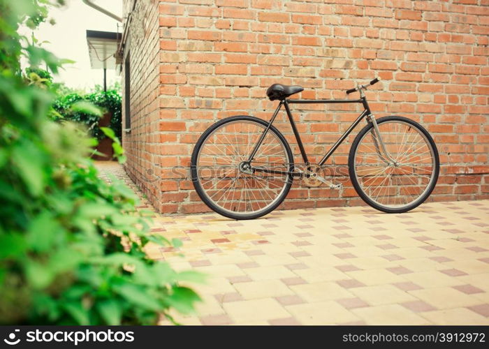 Old style singlespeed bicycle against brick wall, tinted photo