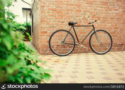 Old style singlespeed bicycle against brick wall, tinted photo