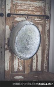 Old stylish iron tub hanging on a wooden wall with grunge paint peeling of the old planks