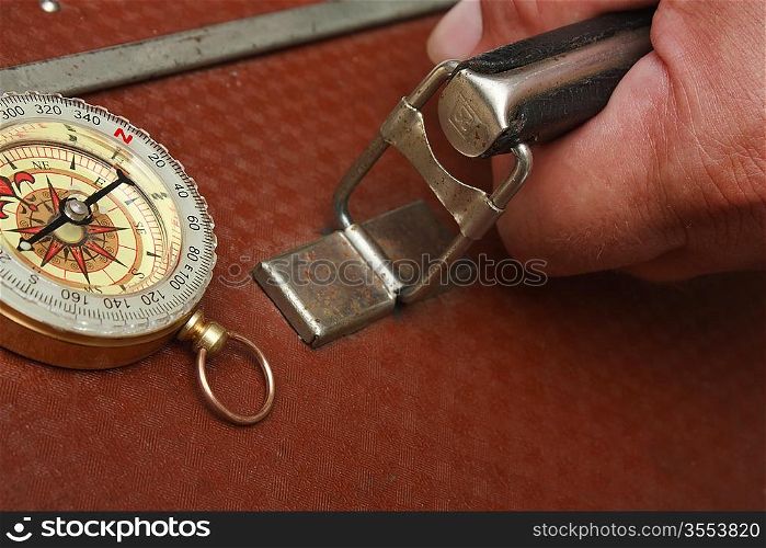 old suitcase in hand and compass isolated on white background