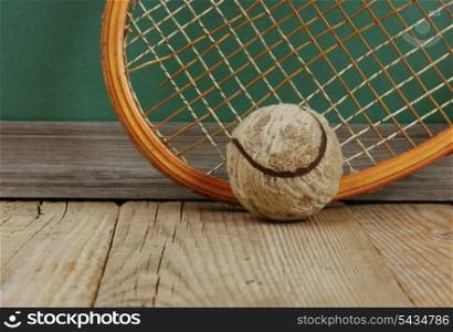 old tennis ball and racket on a wooden floor
