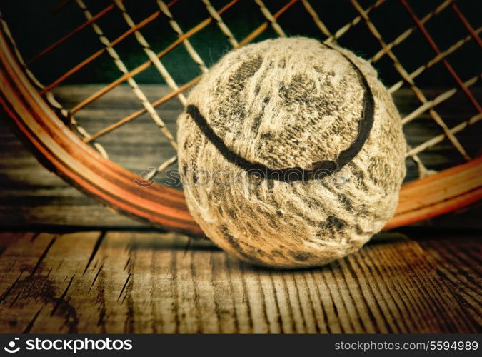 old tennis ball and racket on a wooden floor