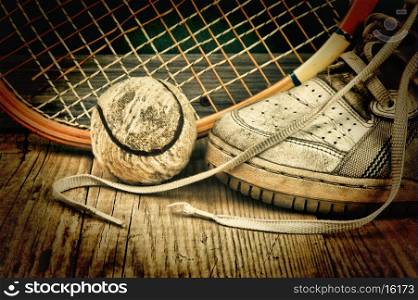 old tennis ball and racket with sneakers on a wooden floor