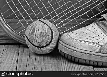old tennis ball and racket with sneakers on a wooden floor