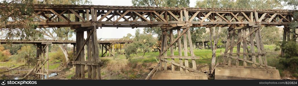 old timber hardwood discontinued railway bridge river crossing in a rural farming town, Victoria, Australia
