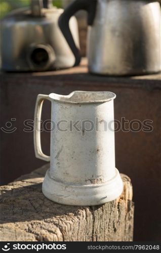 Old tin jug in an outdoor kitchen sitting on aged timber