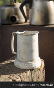Old tin jug in an outdoor kitchen sitting on aged timber