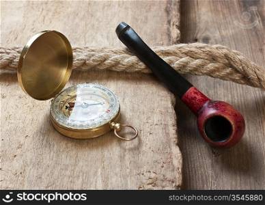 old tobacco pipe and compass on a wooden background